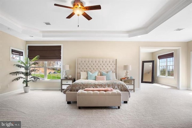 carpeted bedroom with ceiling fan, a raised ceiling, and multiple windows