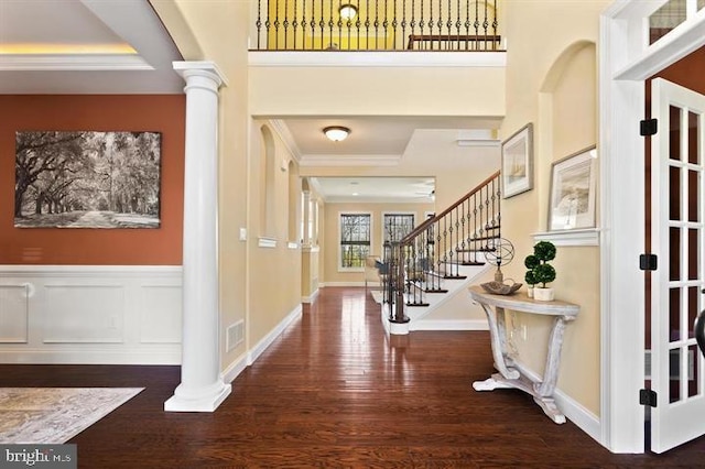 foyer featuring ornamental molding, ornate columns, and dark hardwood / wood-style floors