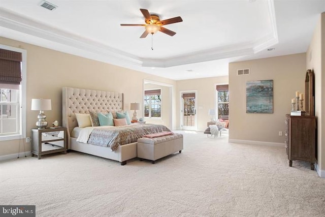 bedroom with light colored carpet, a tray ceiling, and ceiling fan