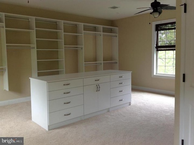 walk in closet with light colored carpet and ceiling fan