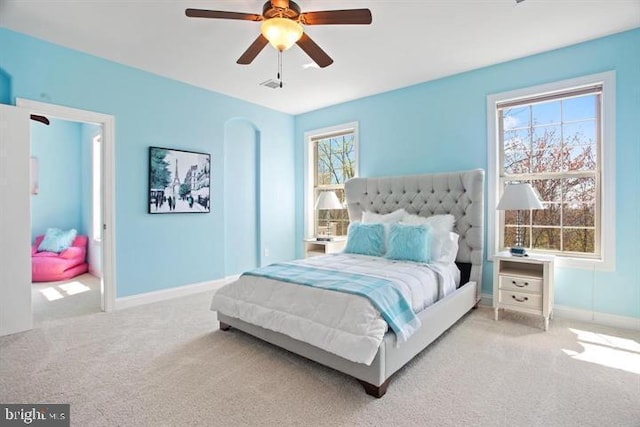 carpeted bedroom featuring multiple windows and ceiling fan