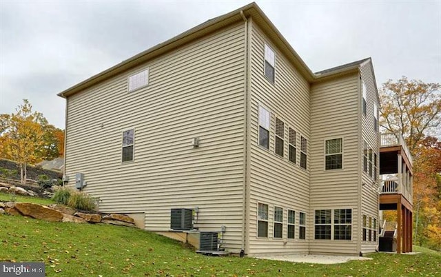 view of side of home featuring a yard, a balcony, a patio area, and central air condition unit