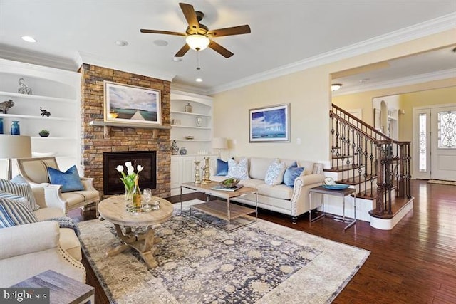 living room with ornamental molding, ceiling fan, dark wood-type flooring, built in features, and a fireplace