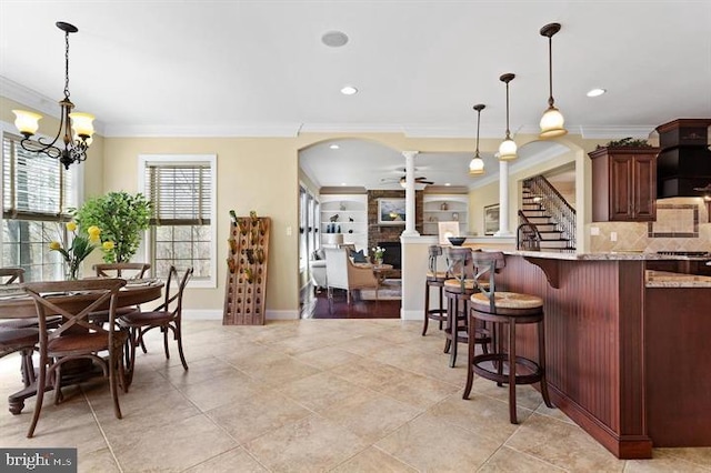 kitchen featuring a breakfast bar area, crown molding, decorative light fixtures, and light stone counters