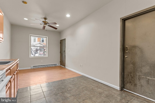 kitchen with ceiling fan, wood-type flooring, baseboard heating, and stainless steel range