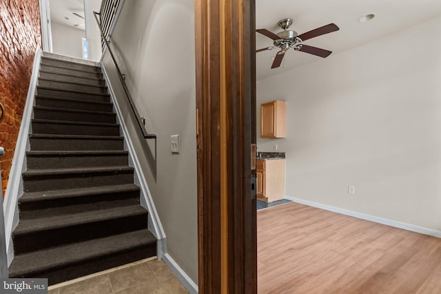 staircase featuring wood-type flooring and ceiling fan