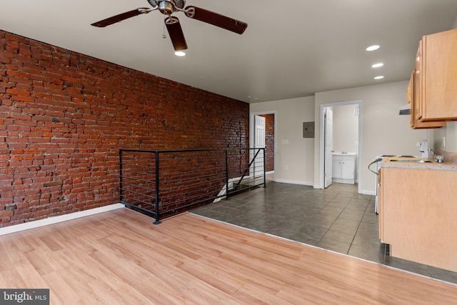 kitchen with ceiling fan, light brown cabinets, brick wall, and light hardwood / wood-style floors