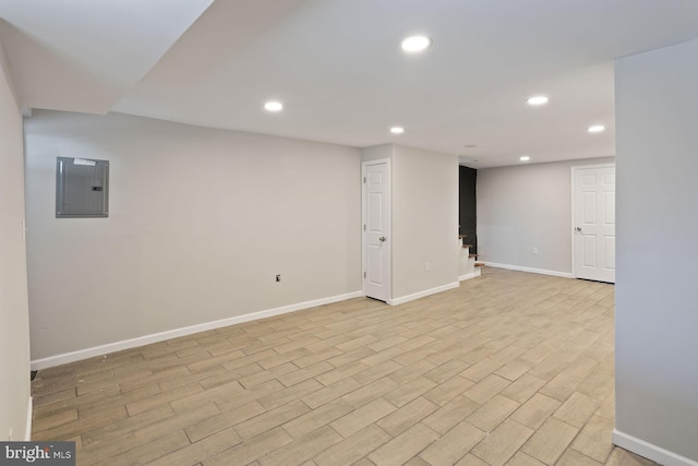 basement featuring light wood-type flooring and electric panel