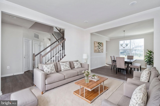 living room with hardwood / wood-style flooring, ornamental molding, and a notable chandelier