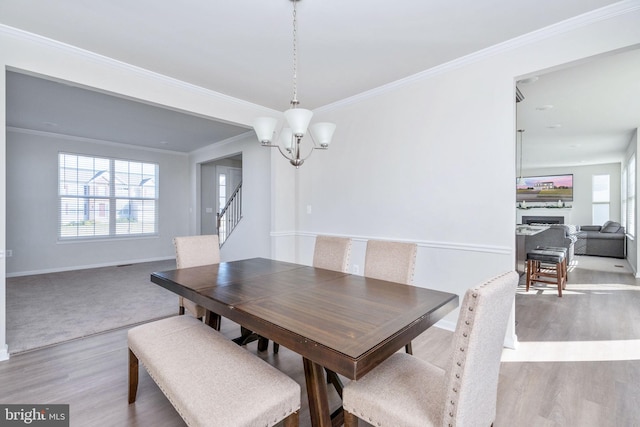 dining room with an inviting chandelier, light hardwood / wood-style flooring, and crown molding