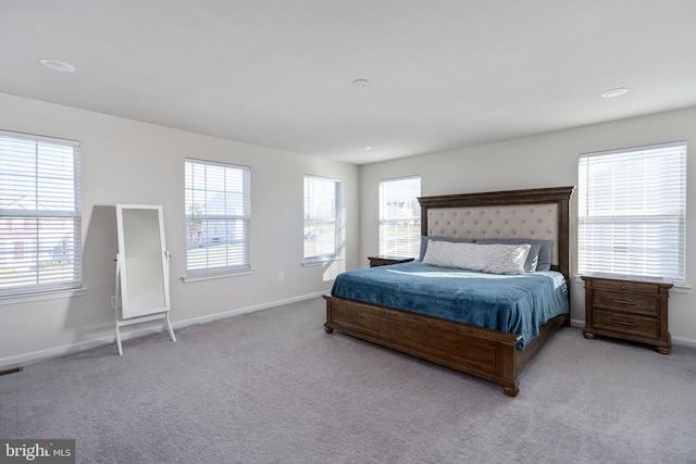 bedroom featuring light colored carpet and multiple windows