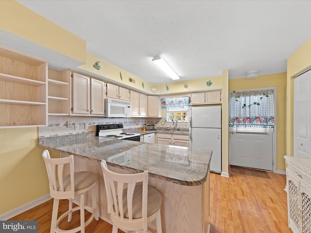 kitchen featuring white appliances, sink, decorative backsplash, light hardwood / wood-style floors, and kitchen peninsula