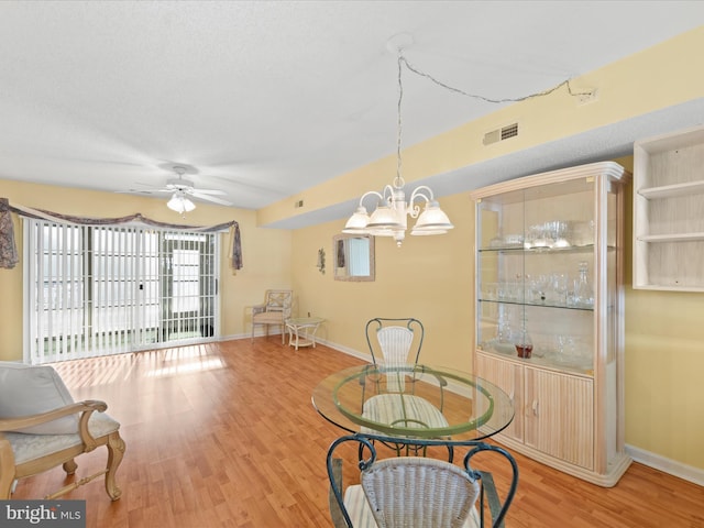 dining area featuring ceiling fan with notable chandelier and wood-type flooring