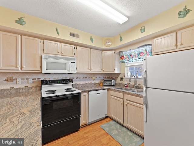 kitchen with light wood-type flooring, light brown cabinets, white appliances, and sink