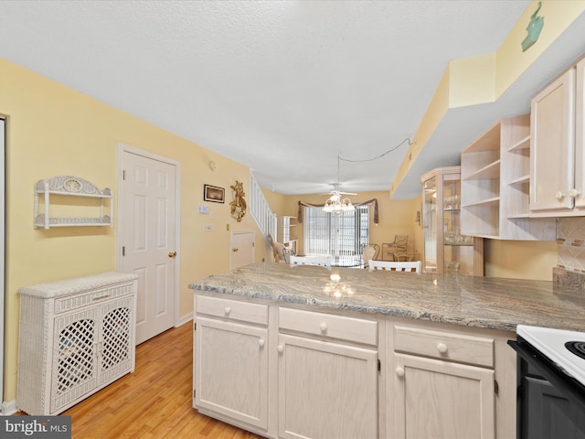 kitchen with kitchen peninsula, light wood-type flooring, ceiling fan, and electric stove