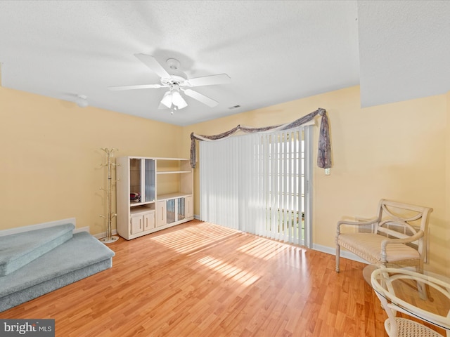 sitting room featuring hardwood / wood-style flooring, ceiling fan, and a textured ceiling