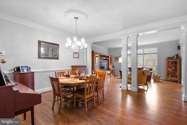 dining room with decorative columns, crown molding, hardwood / wood-style flooring, and a notable chandelier