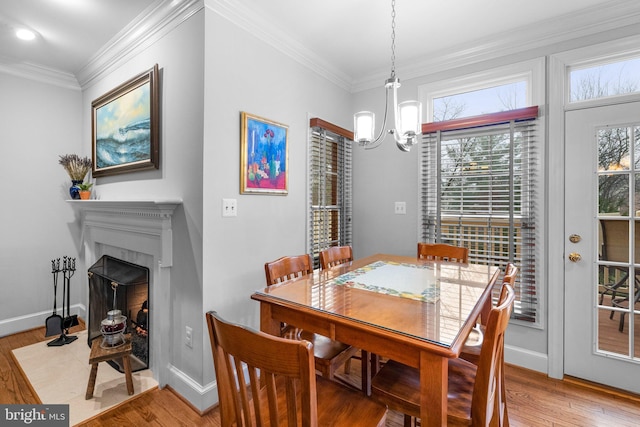 dining area with wood-type flooring, an inviting chandelier, and crown molding