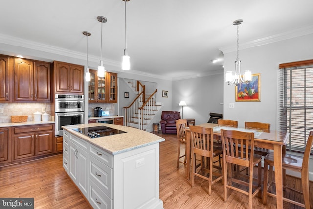 kitchen with white cabinetry, stainless steel double oven, light hardwood / wood-style floors, and backsplash