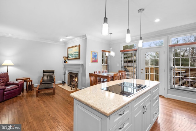 kitchen featuring crown molding, decorative light fixtures, a center island, light hardwood / wood-style flooring, and white cabinets