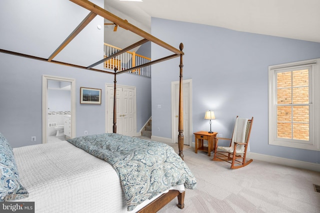 carpeted bedroom featuring high vaulted ceiling and ensuite bath