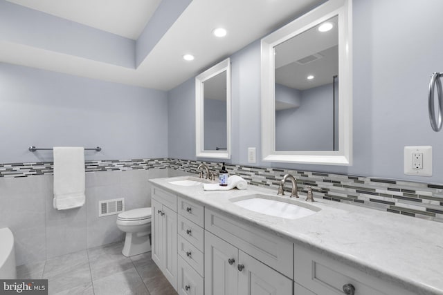 bathroom featuring vanity, tile patterned flooring, tile walls, and toilet