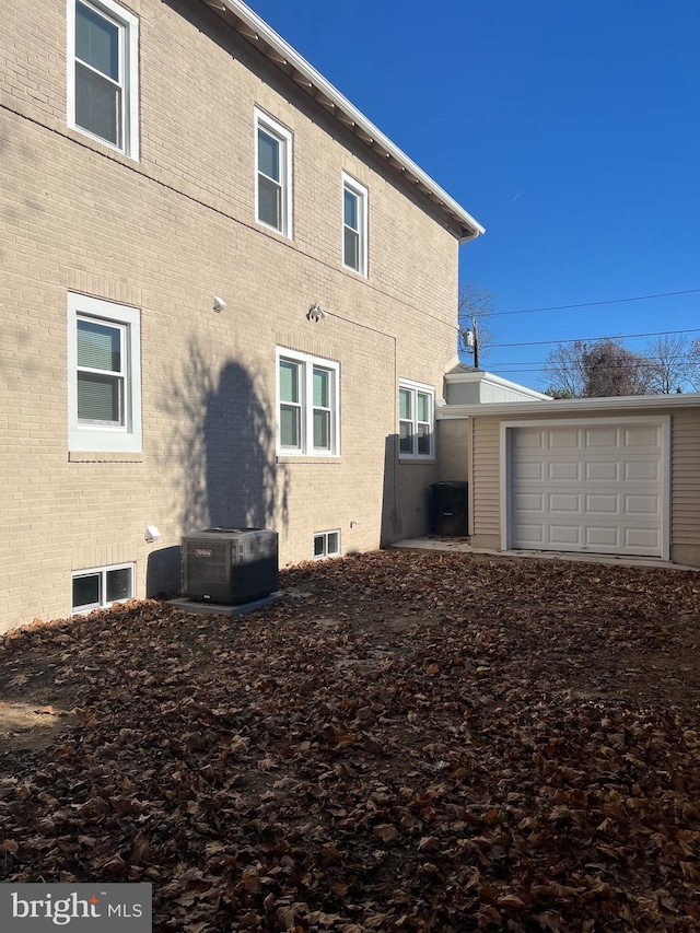 back of property featuring cooling unit, a garage, and an outbuilding