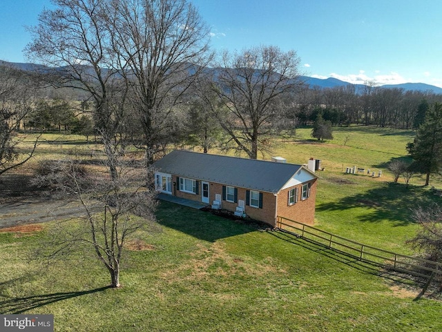 view of front facade featuring a mountain view, a front lawn, and a rural view