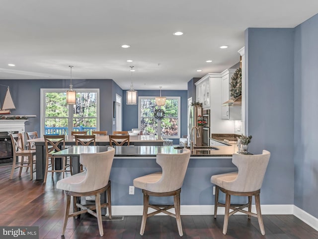 kitchen featuring white cabinets, decorative light fixtures, a kitchen bar, and sink