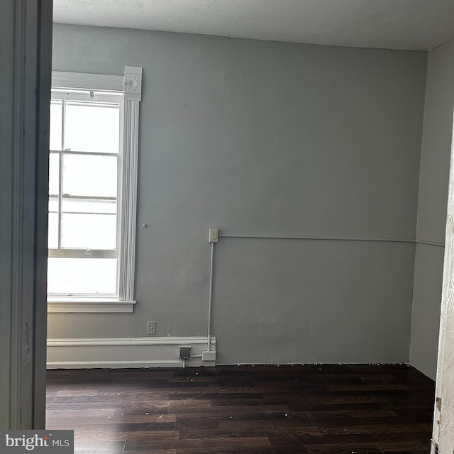 unfurnished room with dark wood-type flooring and a healthy amount of sunlight