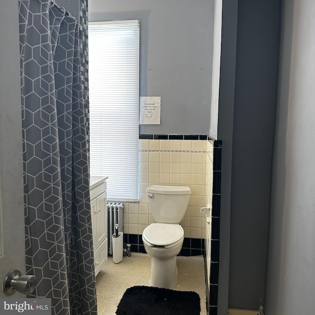 bathroom featuring radiator, vanity, tile walls, and toilet