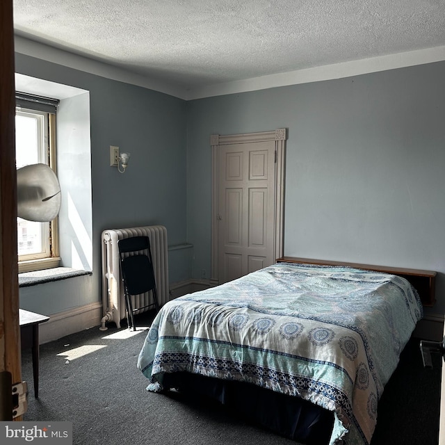 bedroom with carpet, a textured ceiling, and radiator