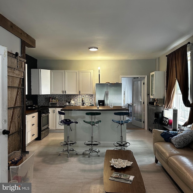 kitchen with backsplash, white cabinetry, a breakfast bar, and stainless steel appliances