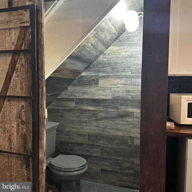 bathroom with wooden walls and toilet