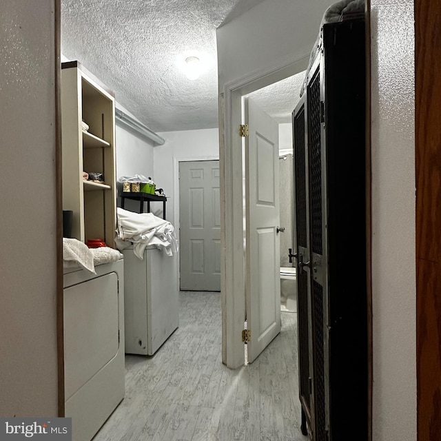 laundry room featuring washer / clothes dryer, a textured ceiling, and light wood-type flooring