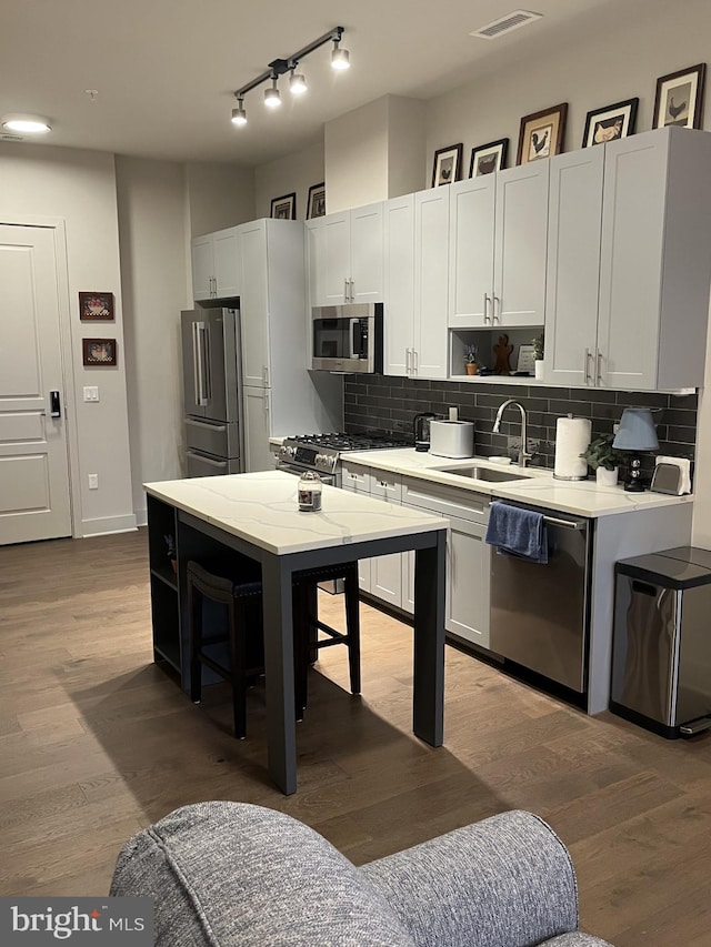 kitchen featuring decorative backsplash, wood-type flooring, white cabinetry, and stainless steel appliances