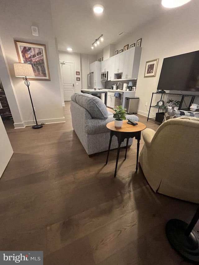 living room with sink, track lighting, and hardwood / wood-style flooring