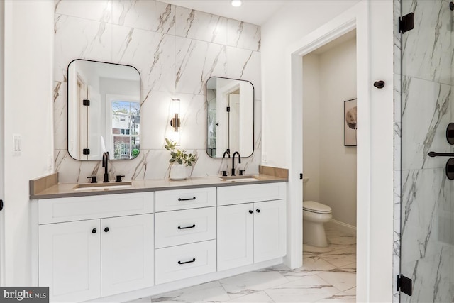 bathroom featuring toilet, marble finish floor, double vanity, and a sink