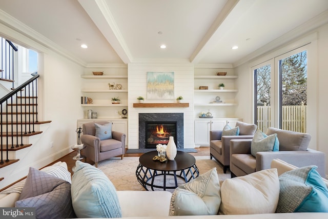 living area with beam ceiling, light wood-type flooring, a glass covered fireplace, and a wealth of natural light