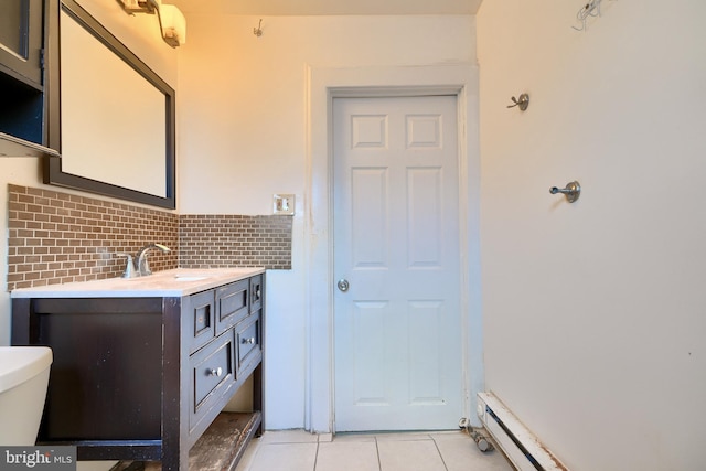 bathroom with baseboard heating, tile patterned flooring, toilet, decorative backsplash, and vanity