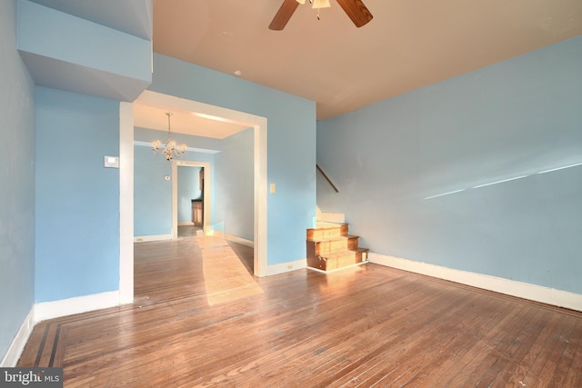 spare room with ceiling fan with notable chandelier and light hardwood / wood-style floors