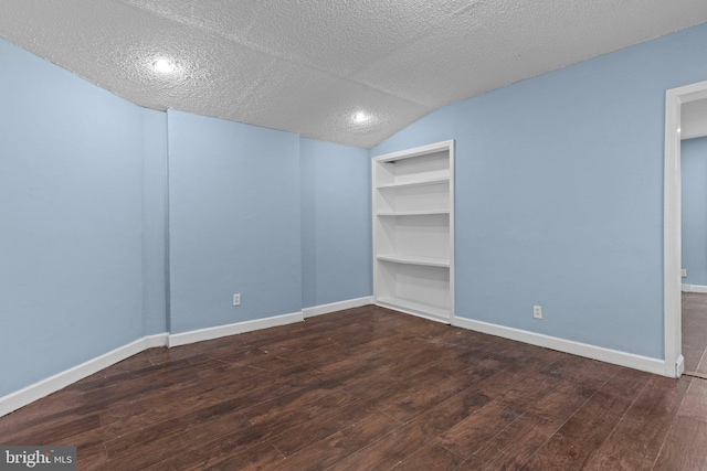 unfurnished room featuring a textured ceiling, dark wood-type flooring, and lofted ceiling