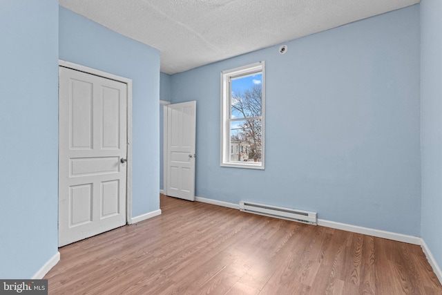 unfurnished bedroom featuring a textured ceiling, light hardwood / wood-style flooring, and baseboard heating