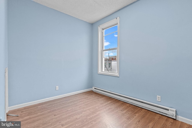 empty room with light hardwood / wood-style flooring, a textured ceiling, and a baseboard heating unit