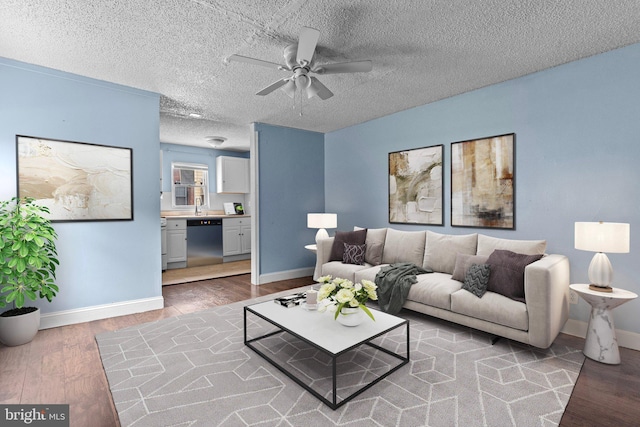 living room with hardwood / wood-style flooring, ceiling fan, and a textured ceiling