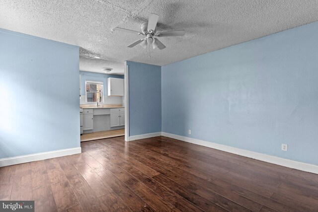 interior space with a textured ceiling, dark hardwood / wood-style floors, ceiling fan, and sink