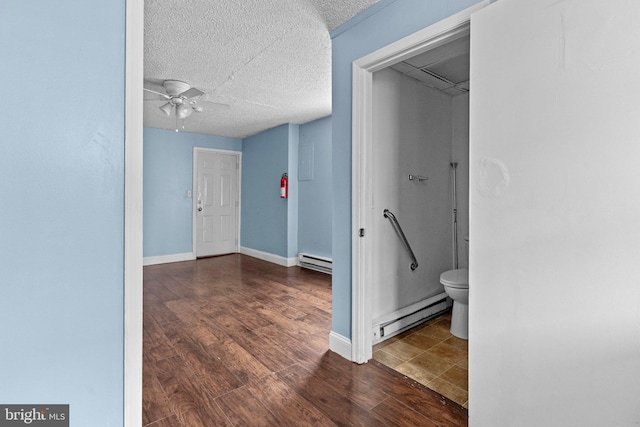 corridor featuring dark wood-type flooring, a textured ceiling, and a baseboard heating unit