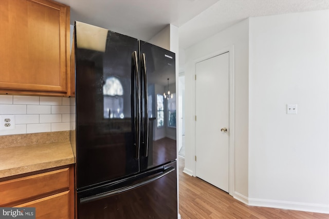 kitchen featuring decorative backsplash, black fridge, and light hardwood / wood-style floors