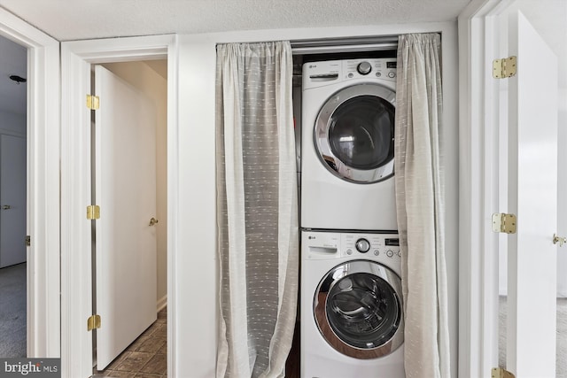 clothes washing area featuring stacked washer and dryer and a textured ceiling