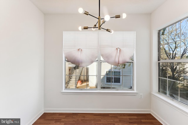 unfurnished dining area featuring wood-type flooring and a notable chandelier